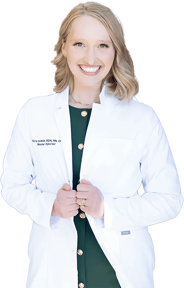 Kiara DeWitt smiling in a white lab coat embroidered with her name and the title Master Injector.