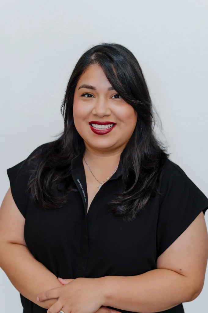Kehila, InjectCo staff member, smiling in a black uniform