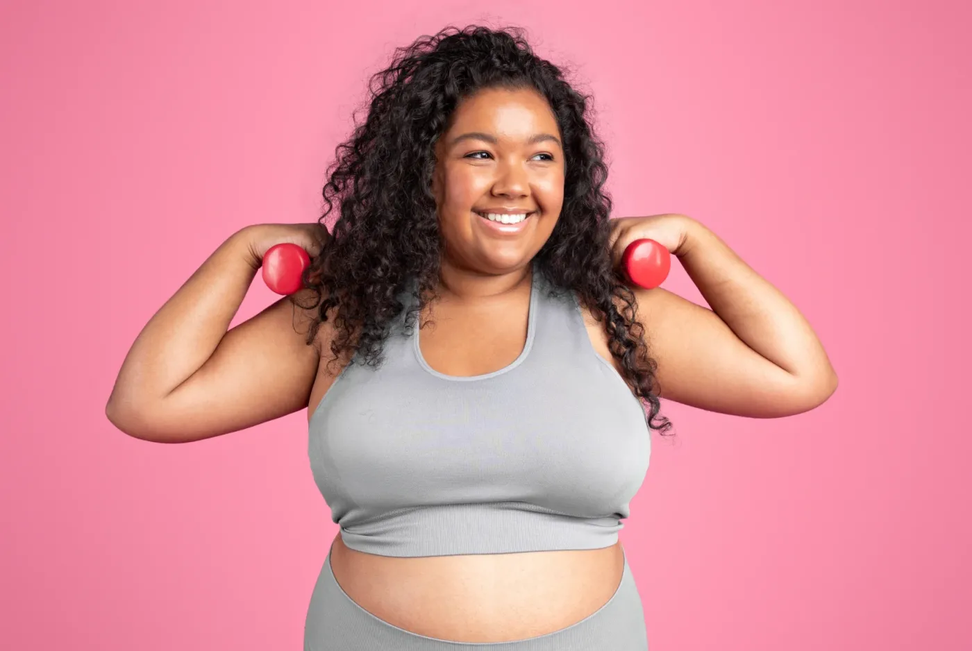 Smiling woman holding a pair of light dumbbells
